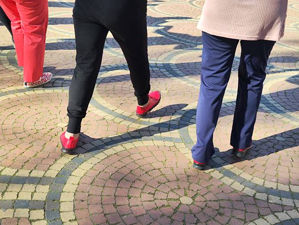 Low section, surface level view of a woman in denims and red canvas shoes walking along an alley in Chinon, France.