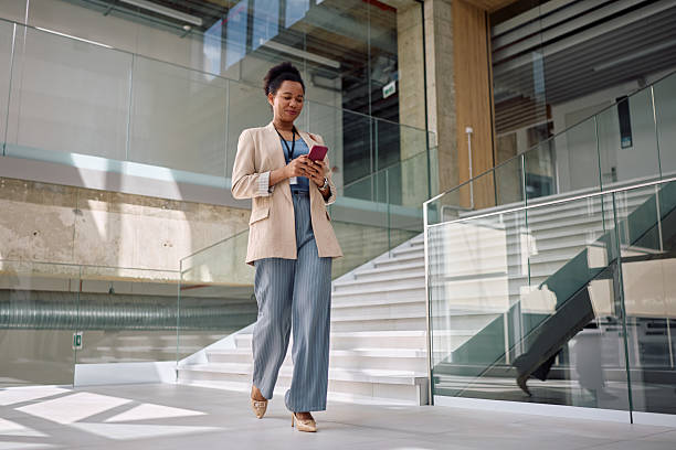 istock Happy black businesswoman using smart phone while walking through the office. 2210091405