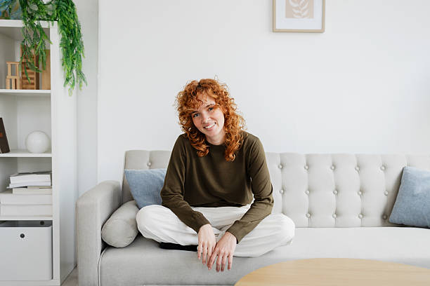 istock Redhead woman smiling and relaxing on comfortable sofa at home 2210094689