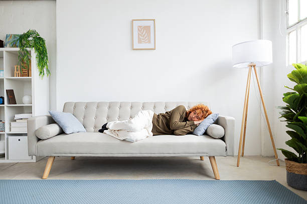 istock Woman sleeping peacefully on sofa in cozy living room 2210096606