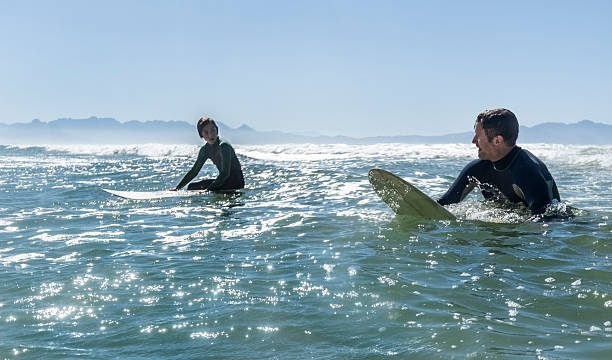 istock Father guiding daughter in surfing during beach weekend 2210103782
