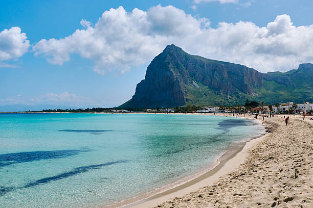 San Vito lo Capo, Sicily, Italy - April 05, 2025: Crystal clear waters lap at a sandy shore of San Vito Lo Capo, Palermo, Italy