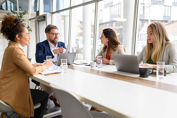 istock Male executive communicating with businesswoman while coworkers analyzing report in professional meeting 2210107143