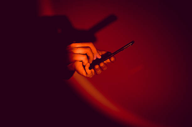 istock Person using smartphone in dark room with red light 2210115053