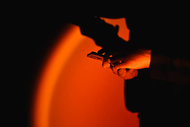 Hands holding mobile phone in dark room illuminated by orange light