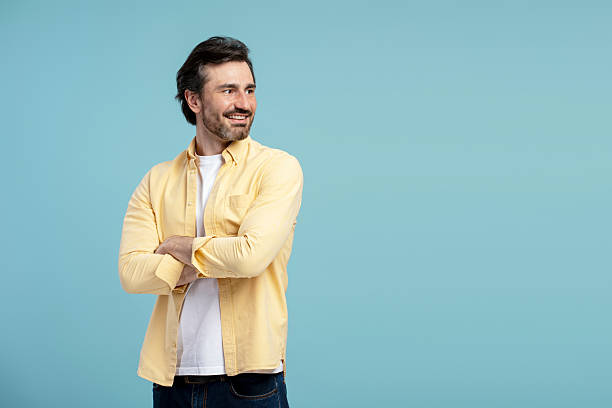 istock Smiling man crossing arms and looking away on blue background 2210117546
