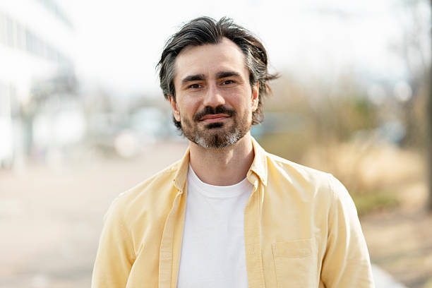 istock Portrait of confident middle-aged man smiling outdoors in urban setting 2210117622