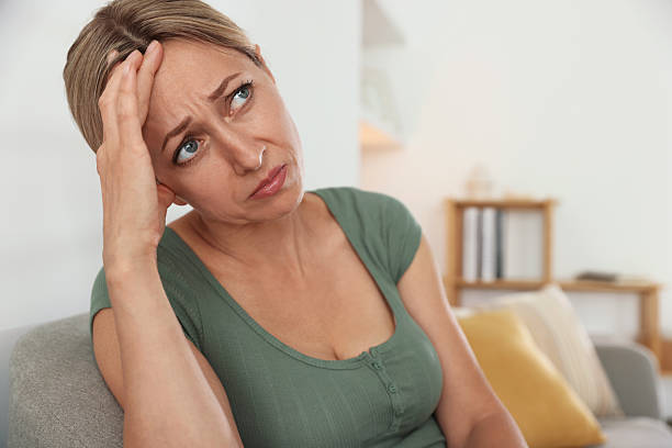 istock Menopause. Woman suffering from headache on sofa at home 2210129558