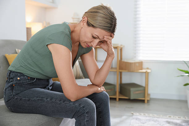 istock Menopause. Woman suffering from headache on sofa at home 2210129590
