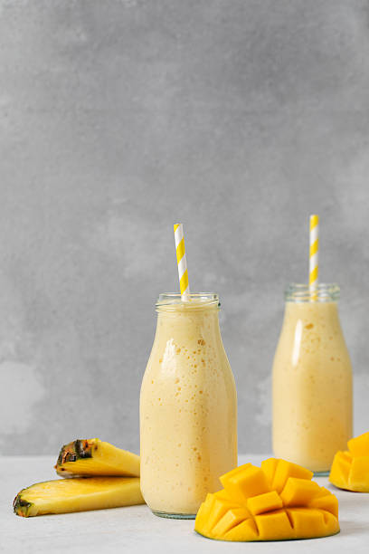 istock Tropical mango pineapple smoothie with fresh fruit garnish on grey background 2210130247