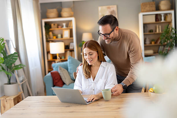 istock Cheerful Woman Working on Laptop with Man Behind Smiling 2210130610