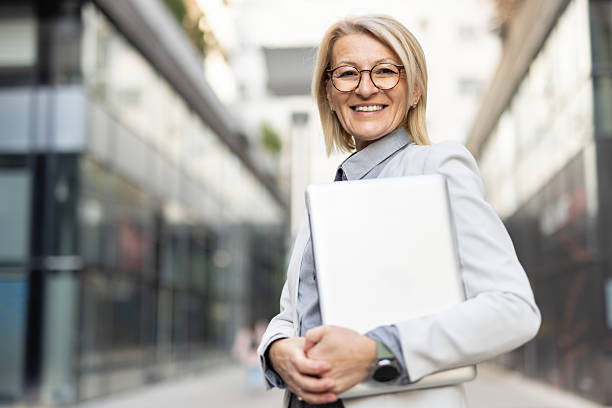 istock Businesswoman smiling with laptop against modern backdrop 2210130791