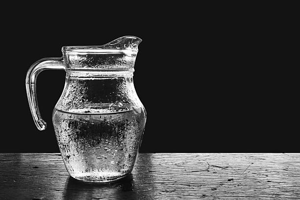 Glass pitcher of cold water on wood table