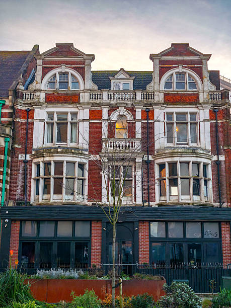 A large brick building with a white trim and a black awning. The building has a lot of windows and a balcony