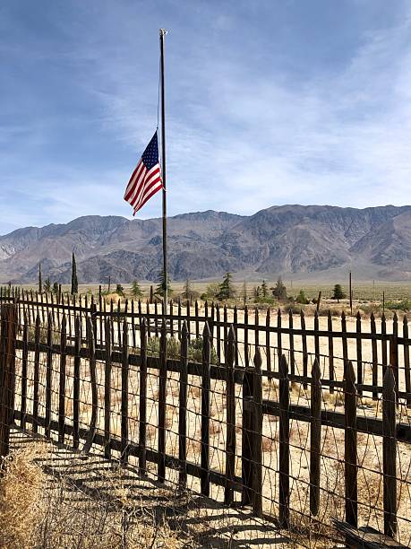 Picket fence around otherwise unmarked grave site, flag at half mast