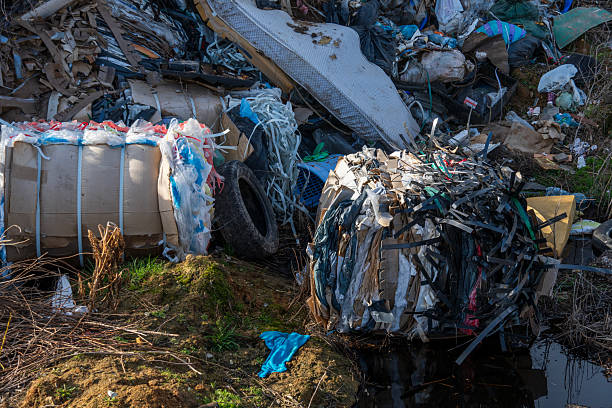 istock Piles of discarded plastic, tires, and cardboard clutter a natural area beside a water source, highlighting severe environmental issues related to pollution 2210147441