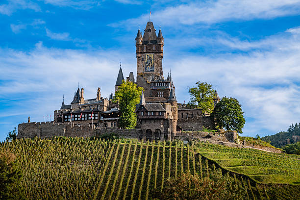 Romantic Moselle river in Germany near Cochem. Beauiful medieval Reichsburg castle on a hill surrounded by colourful autumn forest.