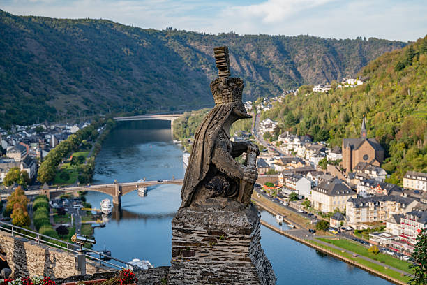 Statue of a knight overlooking the Moselle River, with the picturesque town of Cochem and lush hillsides in the background, captured from Reichsburg Cochem Castle