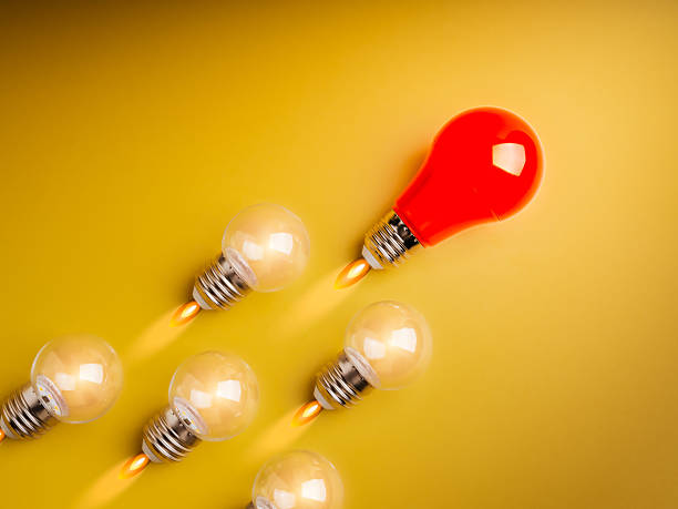 istock Business startup, creative idea, leadership and teamwork concept. Big red one light bulb and clear lightbulbs followers as spaceship or rocket launch with fire smoke on yellow background, minimalist. 2210153174