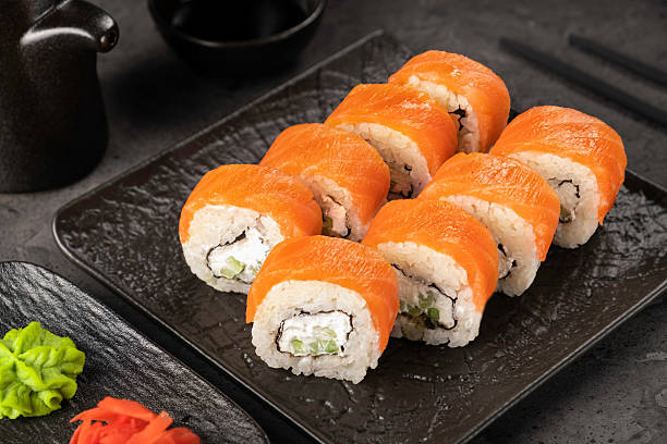istock Fresh salmon sushi rolls with cream cheese and avocado on black plate 2210157526