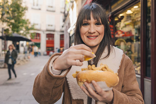 istock Tourist squeezing lemon on fried calamari sandwich in Madrid 2210158638