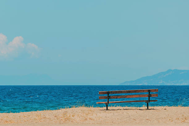 Empty bench at Aegean sea beach in summer, selective focus