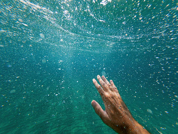 istock Drowning man lifting his hand up through deep ocean water to ask for help and assistance, underwater shot 2210163709