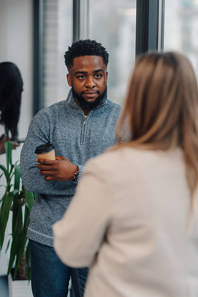 istock Two business colleagues talking during coffee break in office hallway 2210163725