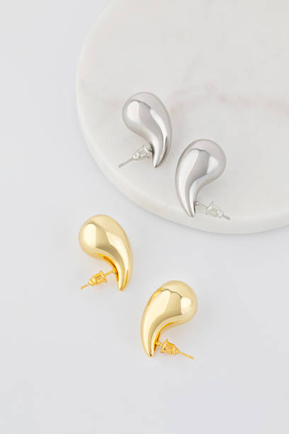 istock Elegant gold and silver droplet earrings resting on marble surface 2210165245