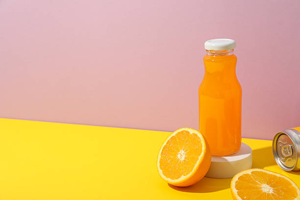 istock Glass bottle with juice and oranges on pink background, space for text 2210165561