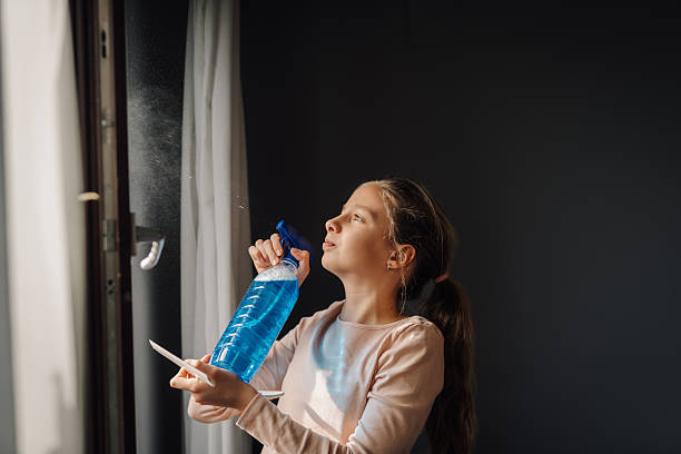 istock Young girl cleaning windows with spray bottle and cloth 2210167009