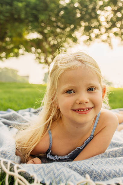 Cute kid girl 2-3 year old with blonde hair wearing denim jacket outdoor over dun light. Looking at camera. Childhood.