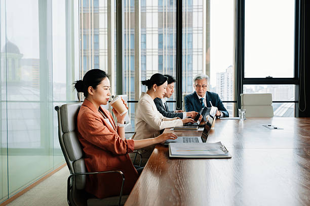istock Confident Asian businesswoman drinking coffee during working on computer in modern meeting room. Focus is on Chinese woman. 2210168718