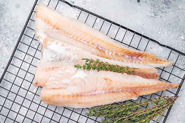 istock Raw pollock white fish fillet with thyme. grey background. top view 2210169518