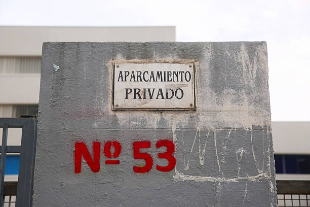 A labeled private parking sign with the number 53 appears on a concrete wall, indicating reserved access. The setting showcases an urban, organized space intended for private parking.