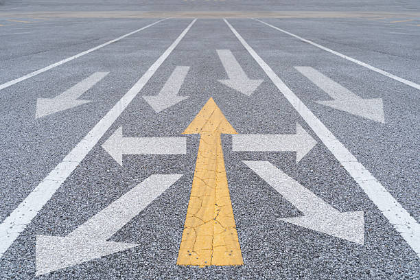 Yellow arrow facing opposite direction white arrows on asphalt street road. Different Thinking.