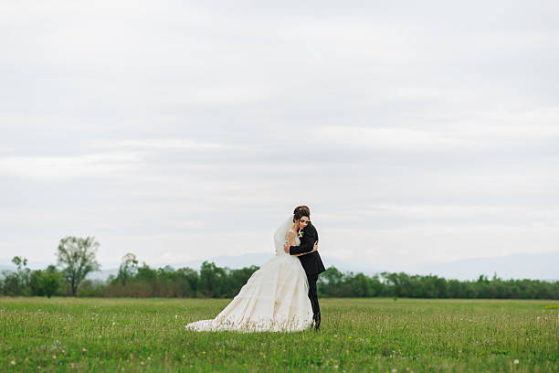 istock A bride and groom are standing in a field, embracing each other 2210174768