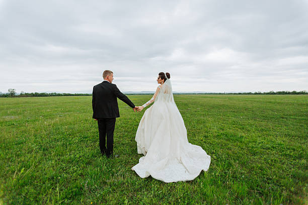 istock A bride and groom are walking in a field on a cloudy day 2210174942