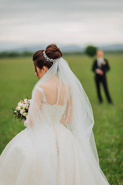 istock A bride is walking in a field with a man behind her 2210174950