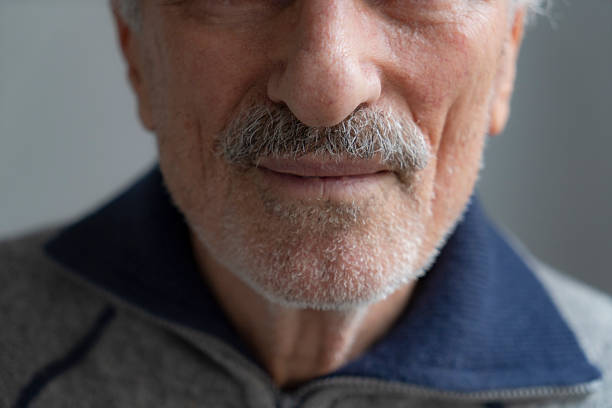 Close up portrait of attractive senior man of 70 years old with blue eyes looking at camera. Retired Caucasian elderly grandfather