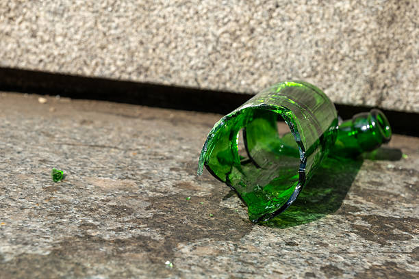 Broken green glass bottle on the pavement of an urban street after a night of celebration at a local event stock photo
