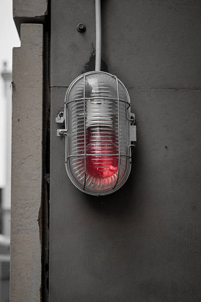 istock Red warning light mounted on a wall, signaling caution in an urban environment during daylight hours 2210177997