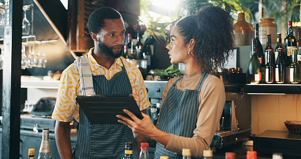istock Restaurant, talking and people on tablet for training for inventory, menu items and checklist by bar. Alcohol, business and man and woman on digital tech for hospitality, service and online order 2210179517