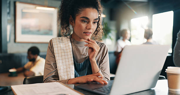 istock Business owner, thinking and woman in restaurant, laptop and problem solving for inventory. Person, employee or barista in coffee shop, tech or online reading for review, decision or report for sales 2210179621