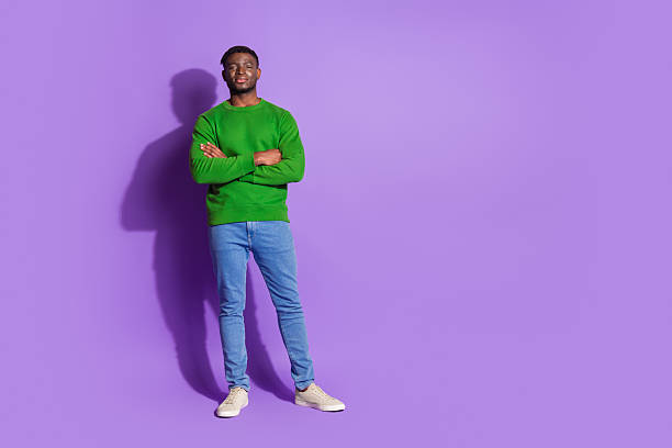 istock Portrait of a casually dressed young man wearing a green pullover standing confidently before a purple backdrop 2210180330