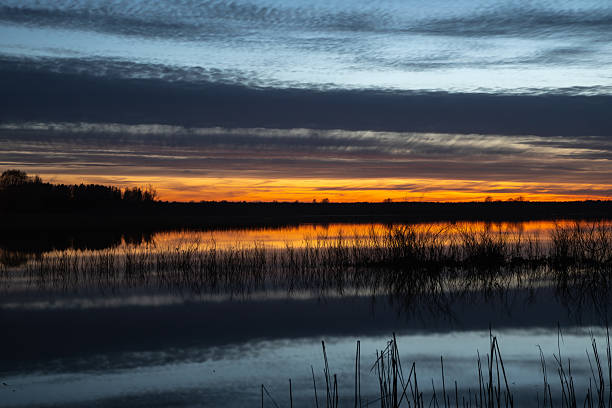 istock Colorful sunset over a calm lake with dramatic clouds and reflections on the water, creating a peaceful and scenic landscape view. 2210181064