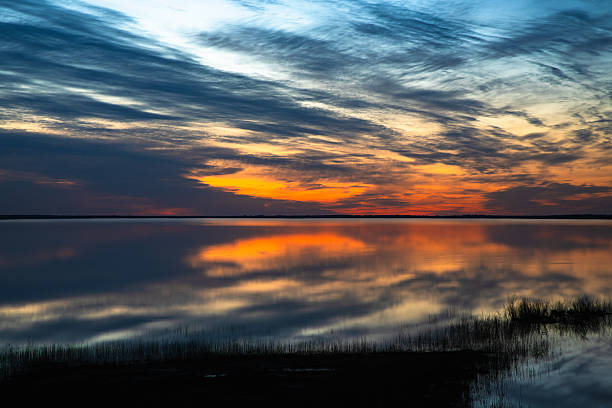 istock Colorful sunset over a calm lake with dramatic clouds and reflections on the water, creating a peaceful and scenic landscape view. 2210181267