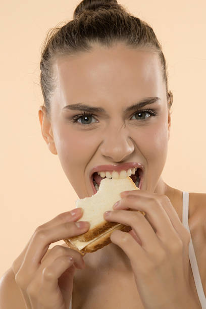 istock Energetic woman devours sandwich with intense, greedy bite, expressing pure culinary enjoyment 2210181393