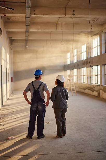istock Back view of a worker making plans with female architect at construction site. 2210182074
