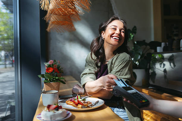 istock Young Woman Using Credit Card After Enjoying Fruit Cake And Coffee 2210182176